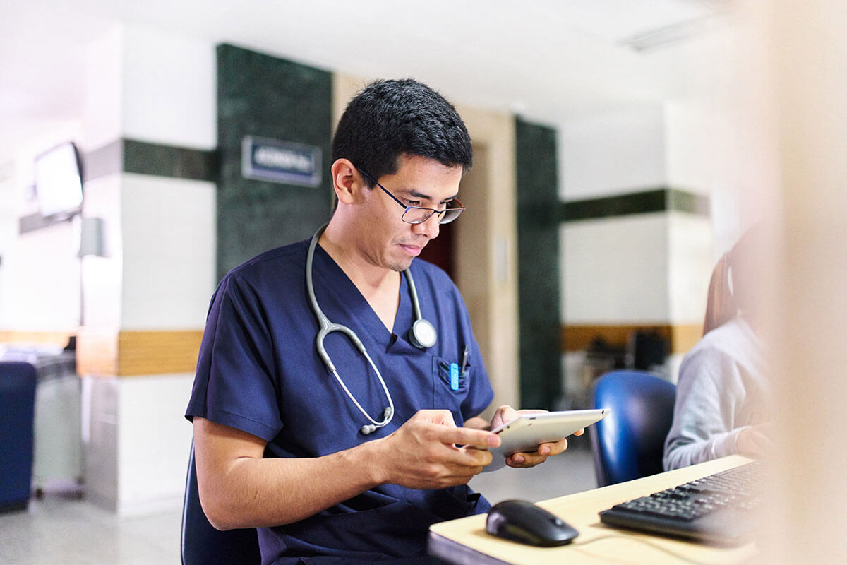 Doctor seated using cloud registry for organ donor on tablet